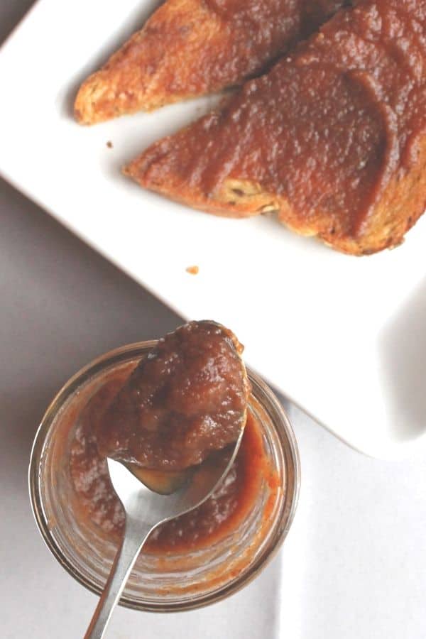 jar of apple butter cooked in the slow cooker, next to pieces of toast