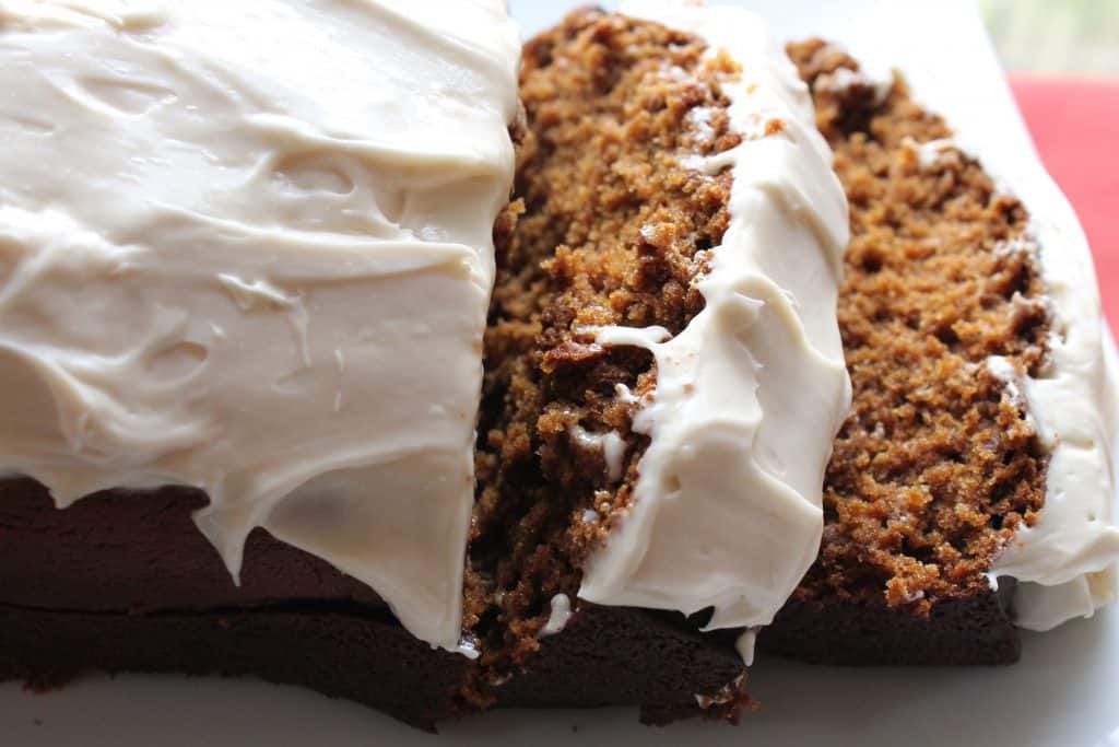 Sliced loaf of gingerbread with maple cream cheese frosting on top