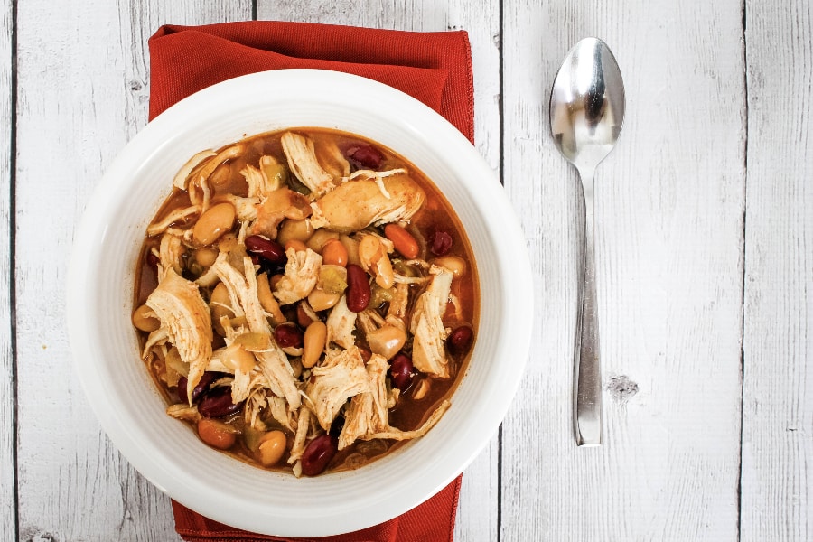 pressure cooker bbq chicken chili in a white bowl atop a red cloth napkin, next to a spoon