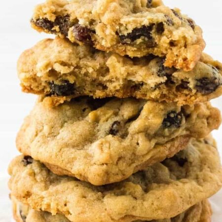 a stack of bakery style oatmeal raisin cookies, with one torn in half to show how soft and chewy it is