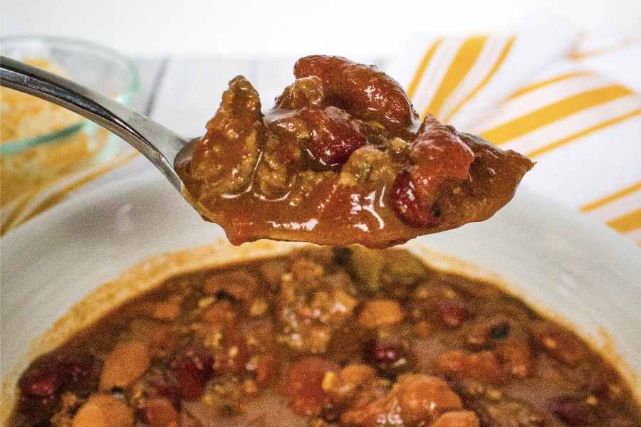 spoonful of pressure cooker ground beef chili above a bowl full of chili