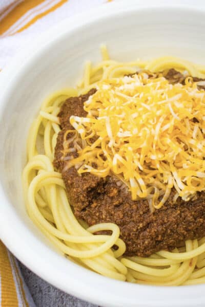 white bowl filled with spaghetti topped with Instant Pot Cincinnati Chili and shredded cheese