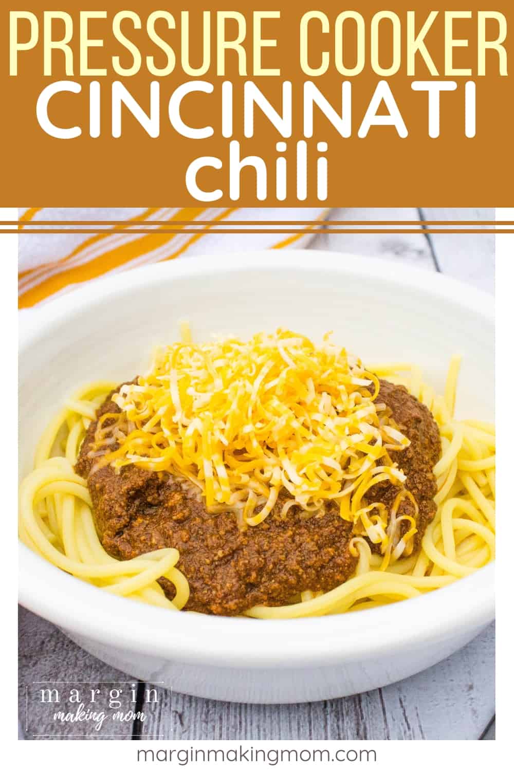 white bowl filled with a bed of spaghetti topped with Cincinnati chili and shredded cheese
