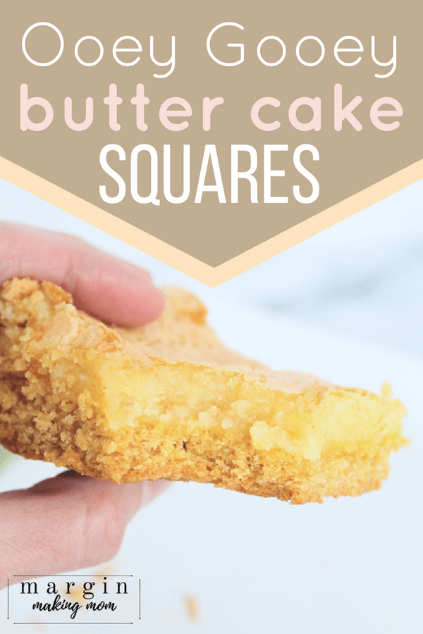 A woman's hand holding an ooey gooey butter cake square with a bite taken out of it