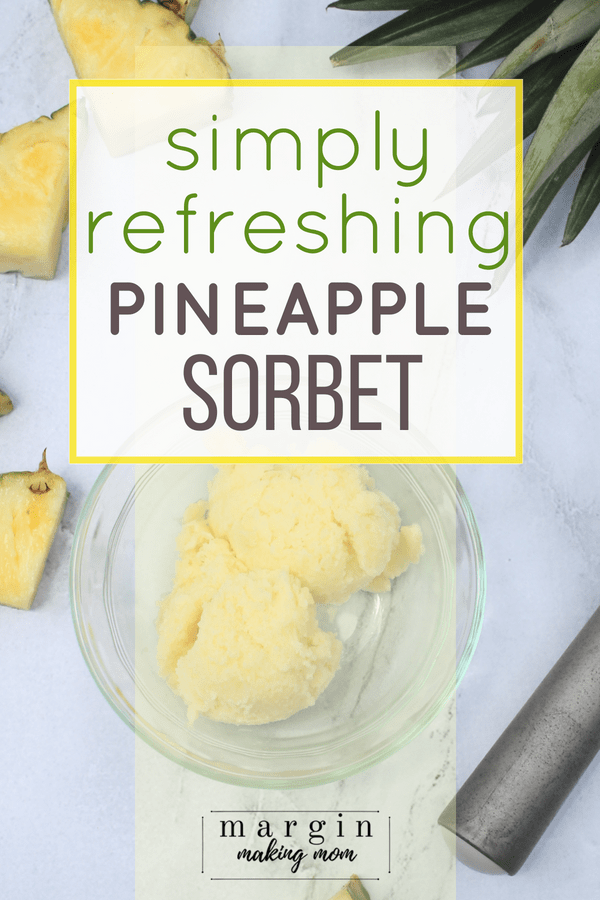 Two scoops of homemade pineapple sorbet in a glass bowl next to pieces of sliced pineapple