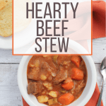 white bowl filled with pressure cooker beef stew, sitting on top of an orange cloth napkin