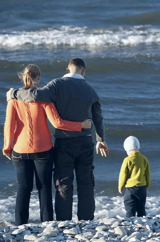 mom and dad with their toddler child at the beach