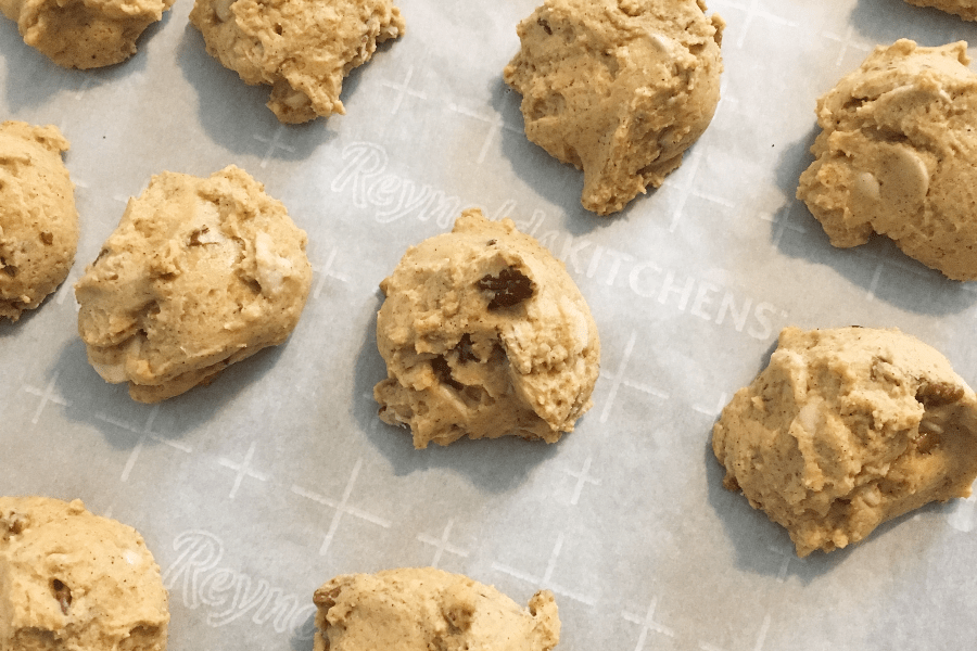 craggy surfaces of pumpkin pecan caramel chip cookies on a parchment lined baking sheet