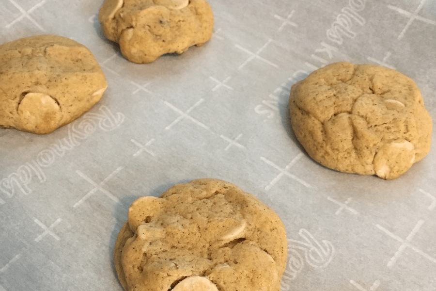 flat surfaces of pumpkin pecan caramel chip cookies on a parchment lined baking sheet