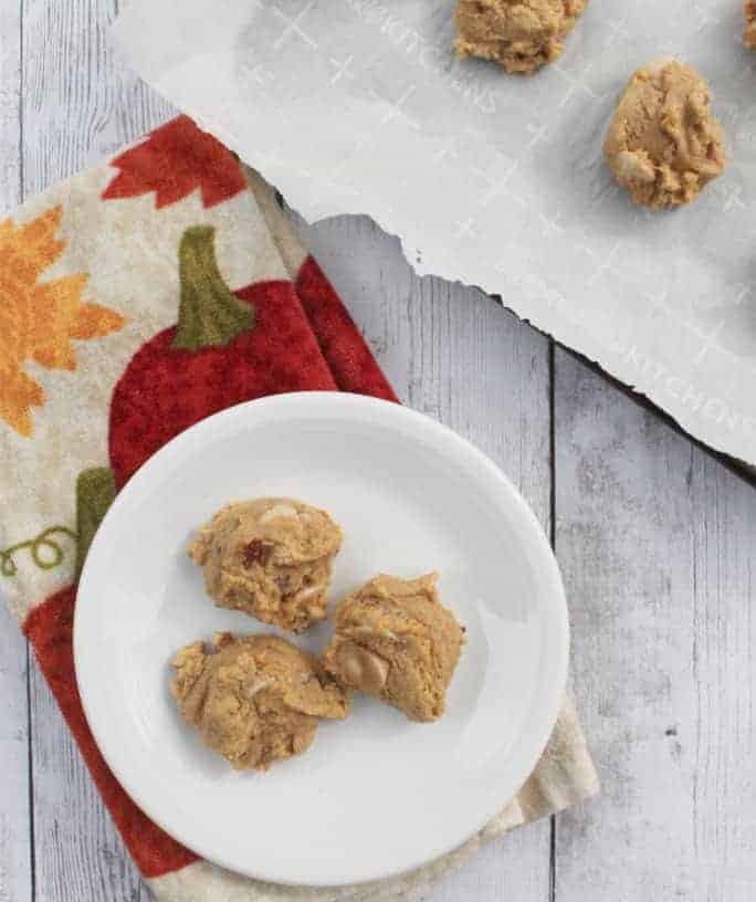 white plate of pumpkin pecan caramel chip cookies resting on a pumpkin printed hand towel