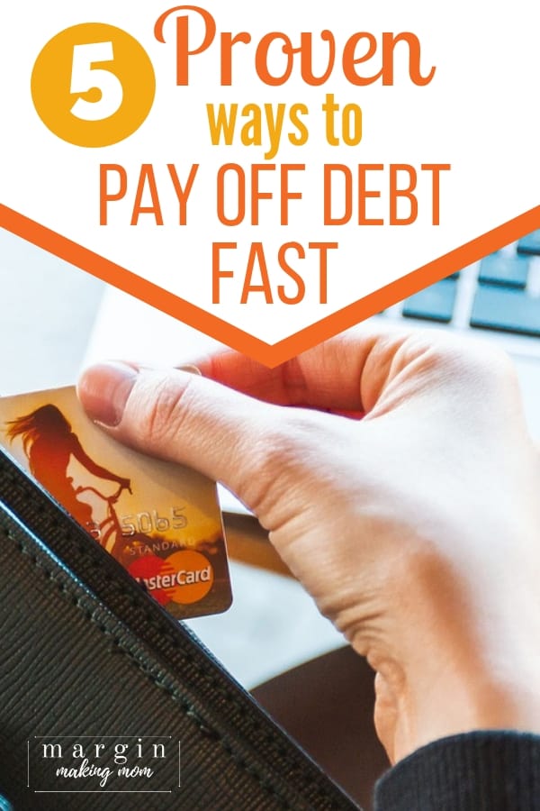 Woman's hand holding a credit card in front of a laptop