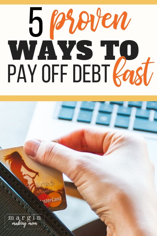 woman's hand holding a credit card in front of a laptop