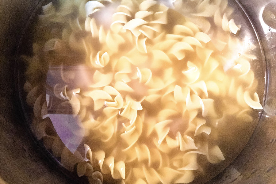 wide egg noodles in the insert pof of an instant pot for making chicken noodle soup