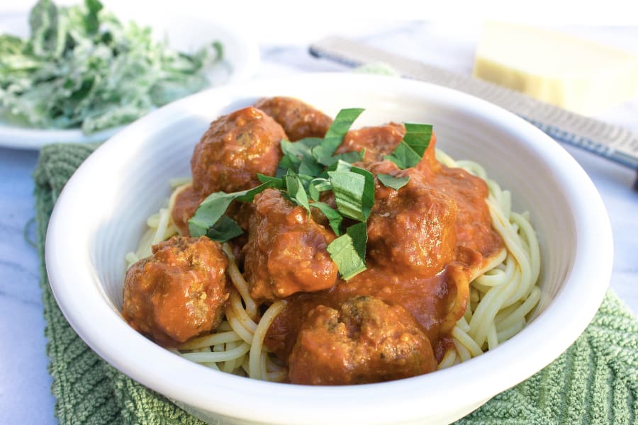 white bowl filled with spaghetti and homemade meatballs with sauce