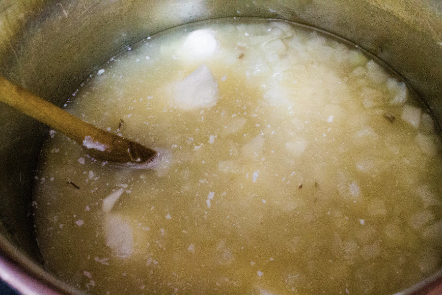 insert pot of an instant pot with potatoes, broth, and cream cheese