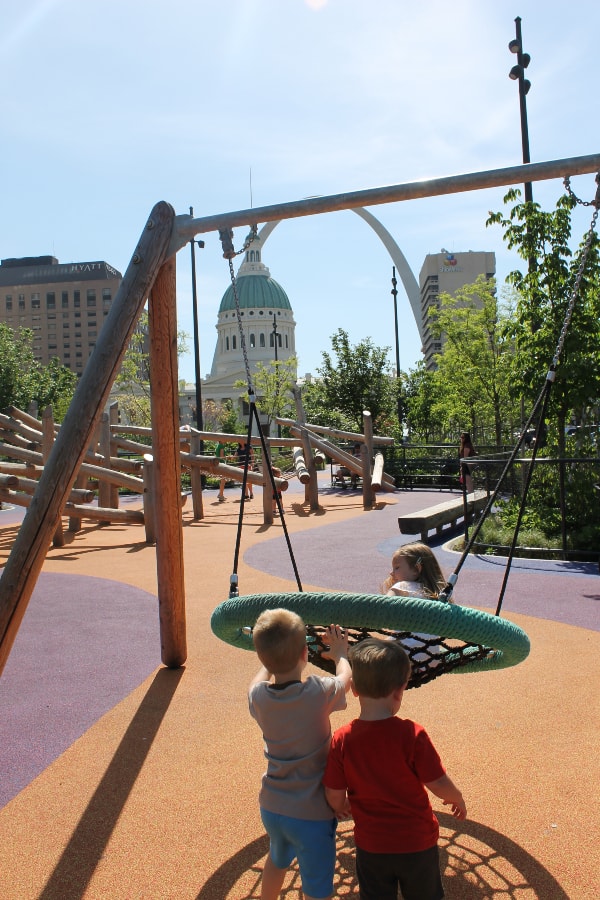 two boys pushing a girl in a swing at kiener plaza park in st louis