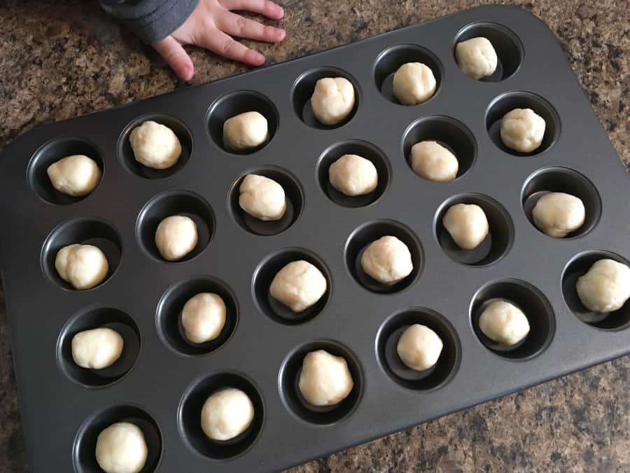 balls of dough for cream cheese crust sitting in the wells of a mini muffin tin