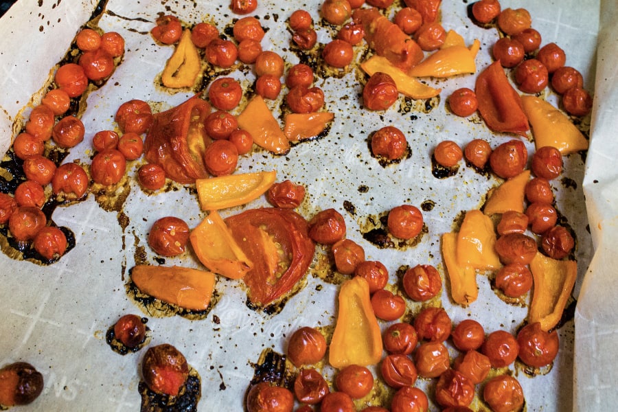 roasted yellow peppers and cherry tomatoes on a parchment lined baking sheet
