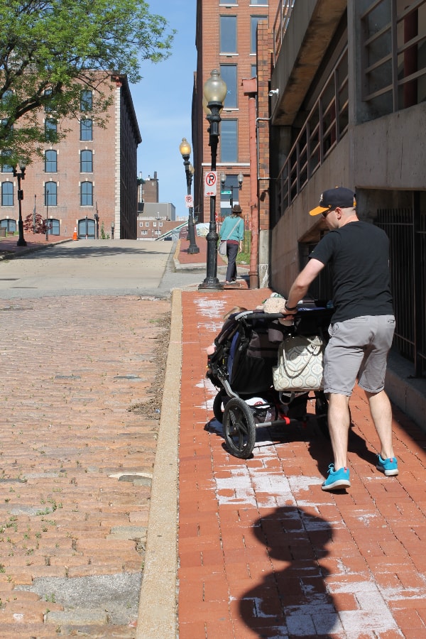 man pushing a stroller through laclede's landing in st louis