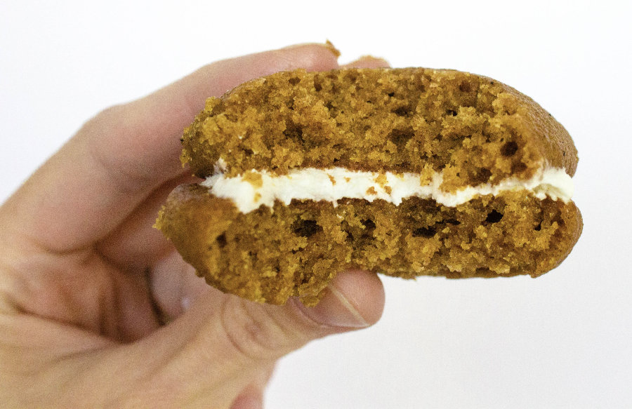 woman's hand holding a pumpkin whoopie pie that has a bite taken out of it