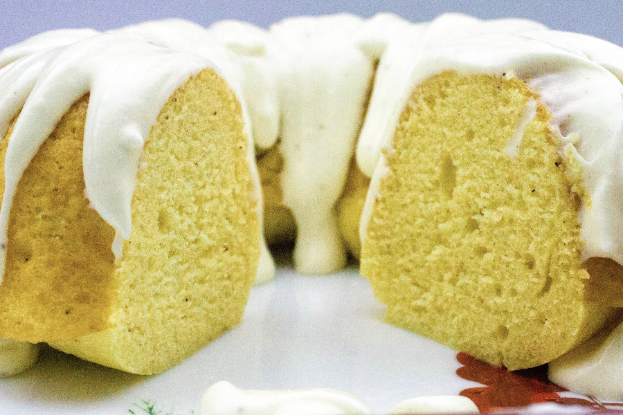 eggnog bundt cake with a slice missing, topped with eggnog cream cheese frosting