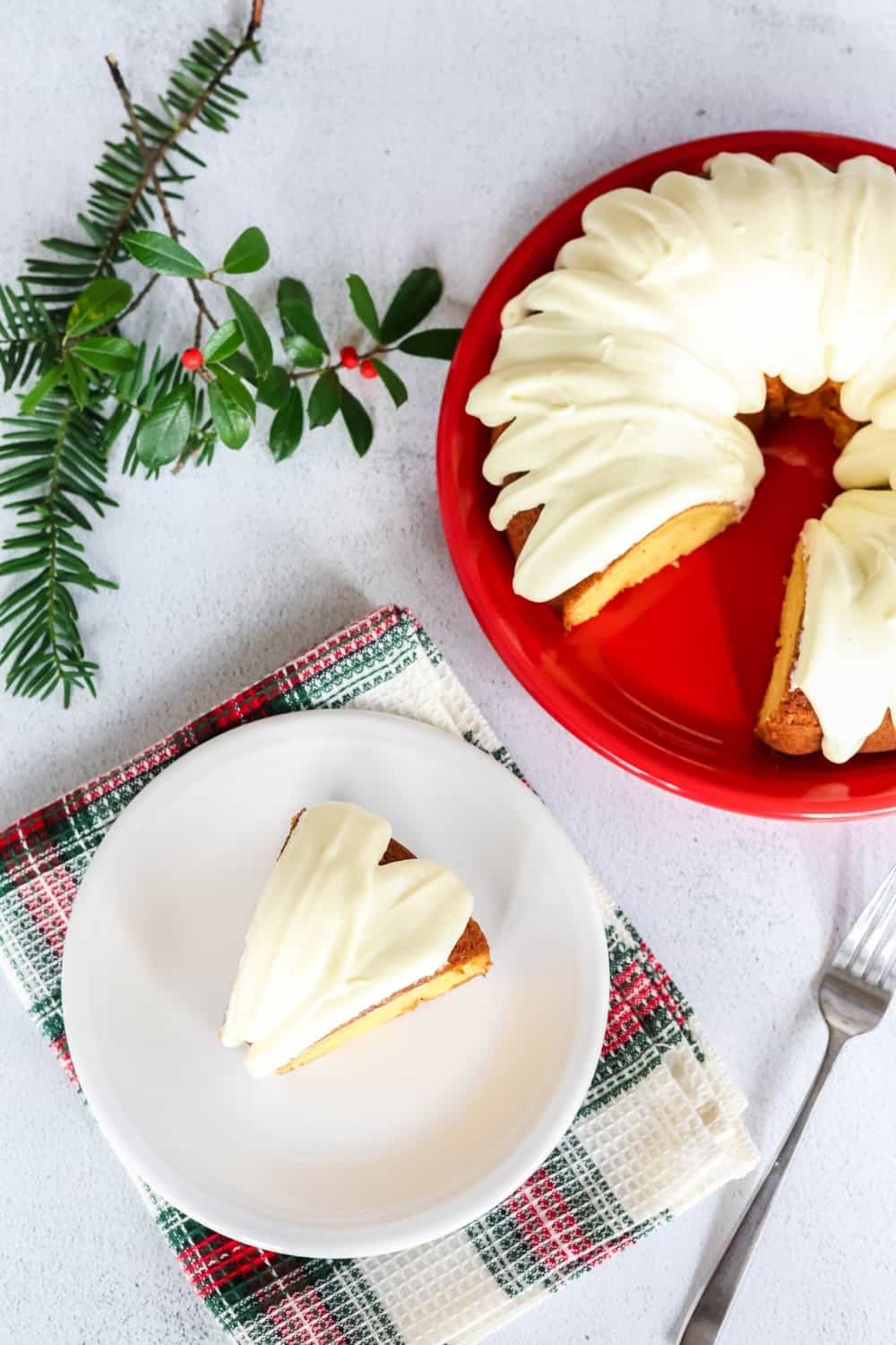 overhead view of a slice of cake mix eggnog bundt cake on a white plate, with the remaining cake on a red platter.