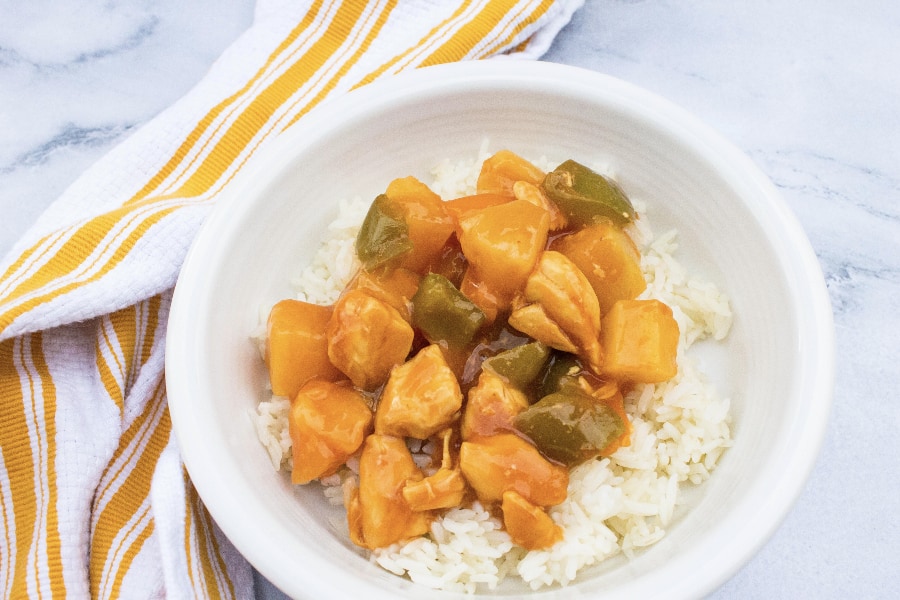 Instant Pot sweet and sour chicken over a bed of rice in a white bowl