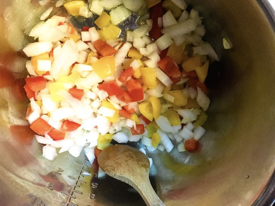 onions, peppers, and olive oil cooking in the Instant Pot to make sweet potato chili