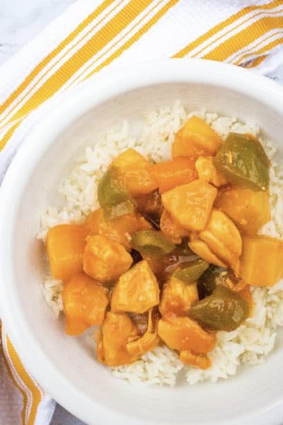 Instant Pot sweet and sour chicken over a bed of rice in a white bowl