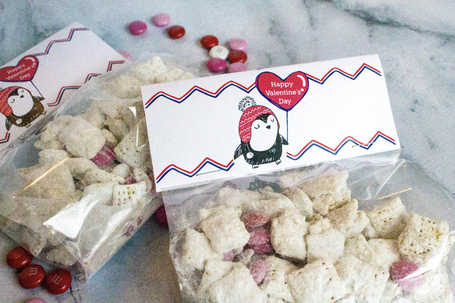 Valentine treat bags adorned with penguin bag toppers and filled with Valentine's snack mix