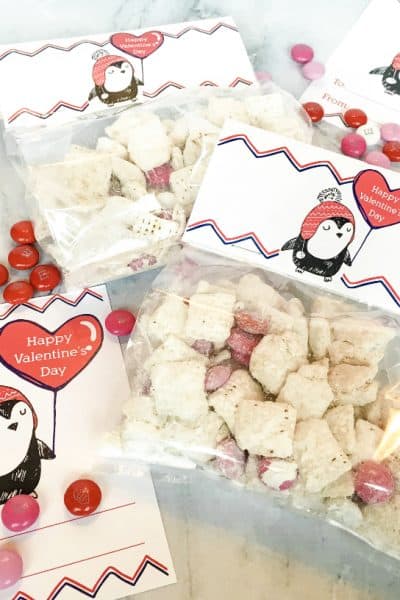 Valentine goodie bags filled with snack mix and topped with free printable penguin bag toppers
