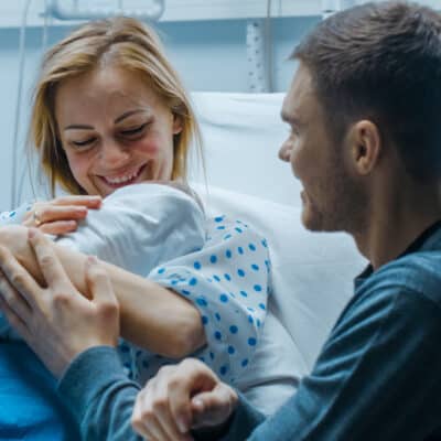 In the Hospital Mother Hold Newborn Baby, Supportive Father Lovingly Hugging Baby and Wife.