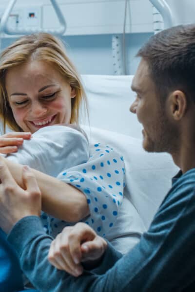 In the Hospital Mother Hold Newborn Baby, Supportive Father Lovingly Hugging Baby and Wife.