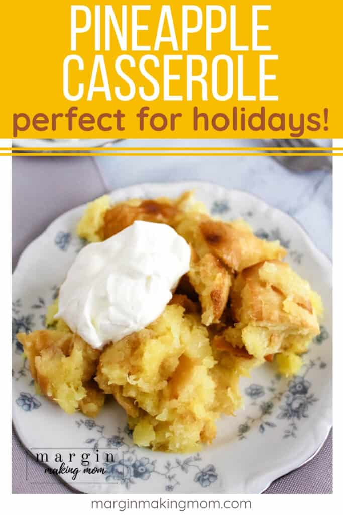 white and blue china plate with a serving of pineapple casserole topped with a dollop of whipped cream