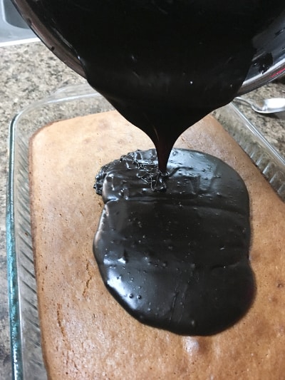 stovetop chocolate frosting being poured over an old fashioned peanut butter cake