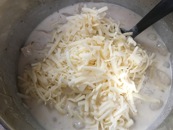 shredded Monterey Jack cheese being added to Instant Pot bacon chicken ranch gnocchi