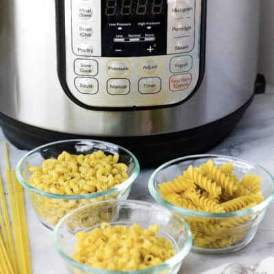 three glass bowls of dried pasta resting in front of an Instant Pot pressure cooker, demonstrating types of pasta that can be cooked in the Instant Pot