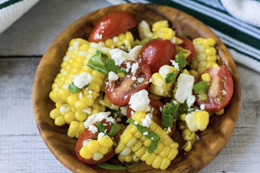 wooden bowl filled with corn and tomato salad, made with corn cooked in the Instant Pot