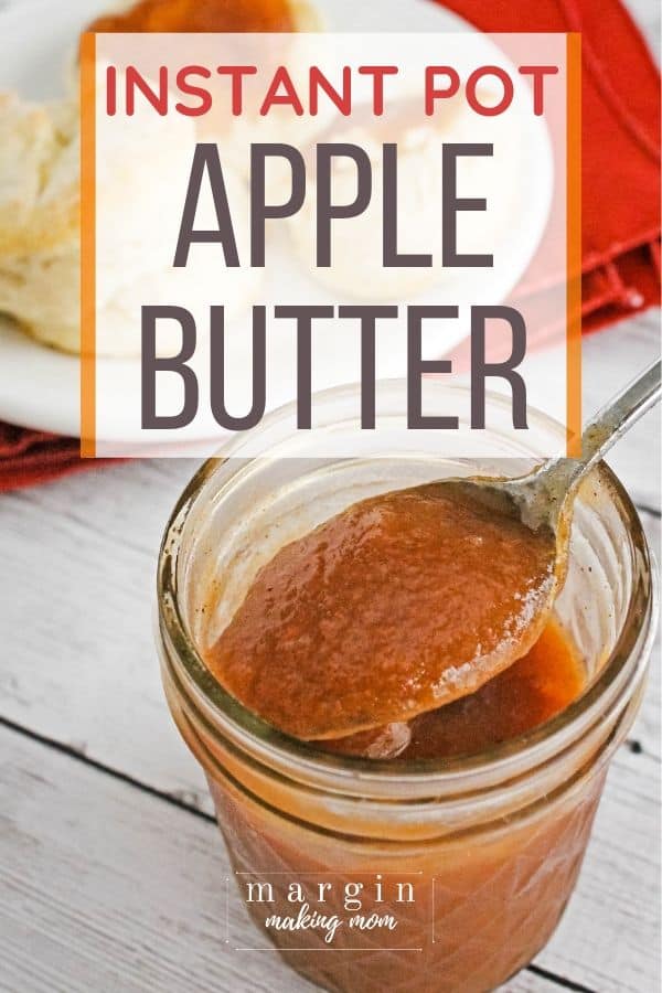 Jar of Instant Pot apple butter, with a spoon removing a scoop