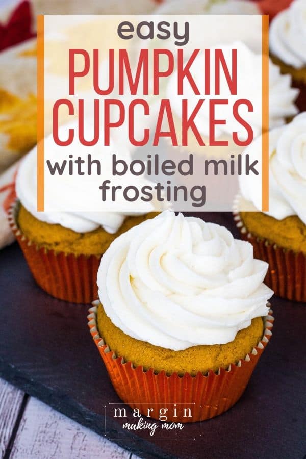 Pumpkin cupcakes topped with boiled milk frosting, resting on a black slate board.