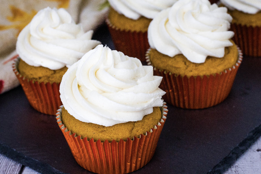 Moist pumpkin cupcakes topped with light and fluffy boiled milk frosting, resting on a black slate tray