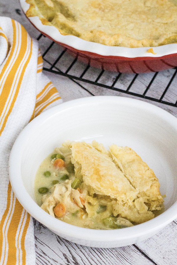 white bowl filled with a serving of Instant Pot chicken pot pie topped with a flaky pie crust