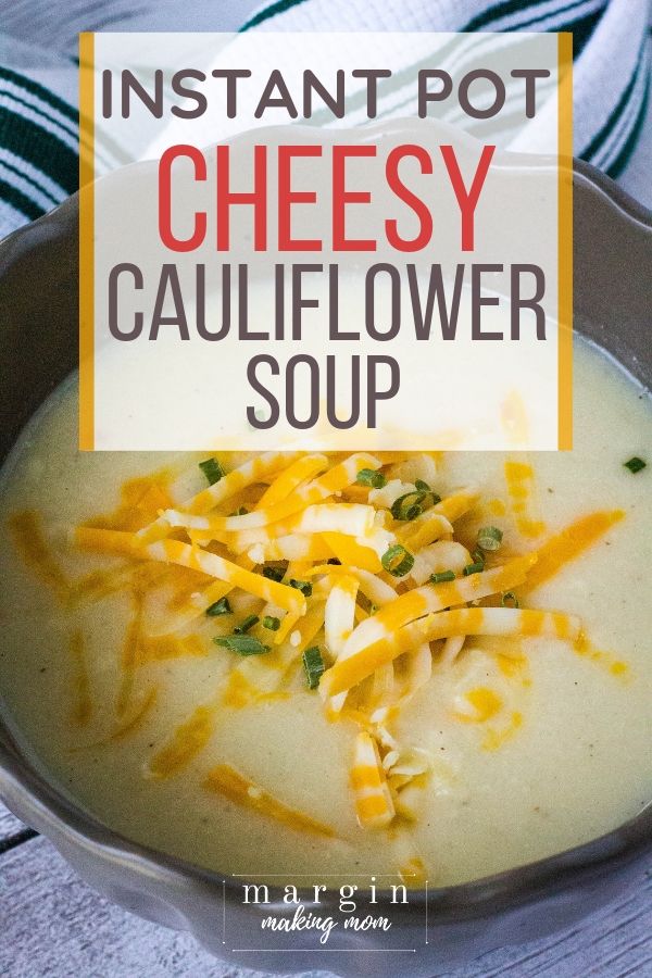 brown bowl filled with Instant Pot cheesy cauliflower soup, topped with shredded cheese and chives