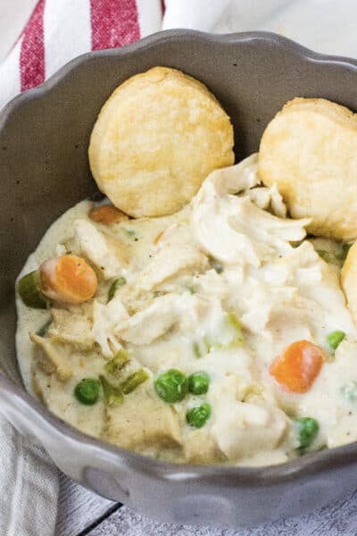 Instant Pot chicken pot pie filling in a brown bowl, served with biscuits