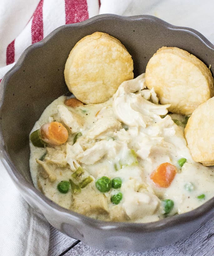 Instant Pot chicken pot pie filling in a brown bowl, served with biscuits