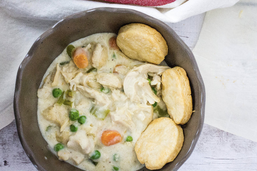 brown bowl filled with Instant Pot chicken pot pie filling and rounds of baked pie crust