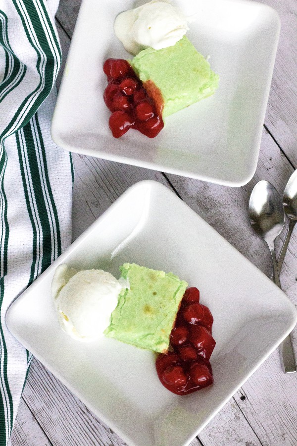 pistachio butter cake served on a white plate with cherry compote and vanilla ice cream