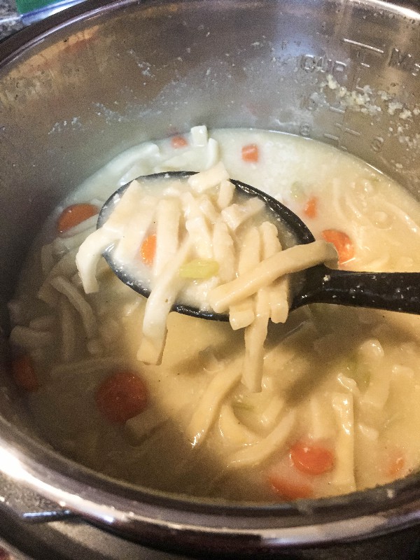 Serving spoon scooping chicken and noodles cooked in the Instant Pot