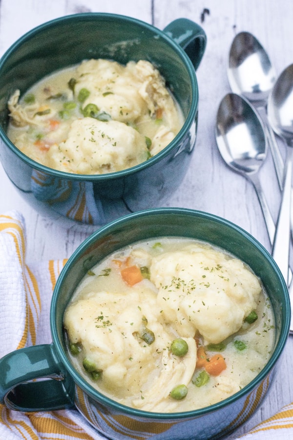 Two green soup mugs filled with chicken and drop dumplings.