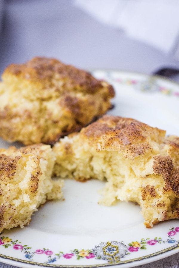 Fluffy drop biscuits topped with cinnamon sugar and a glaze, sitting on a china plate